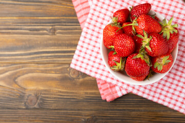Fresh ripe strawberries in a bowl on a brown texture background.Vegetarian organic berry.Healthy food.Copy space.Place for text