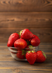 Fresh ripe strawberries in a bowl on a brown texture background.Vegetarian organic berry.Healthy food.Copy space.Place for text