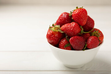Fresh ripe strawberries in a plate on a white wooden background.Vegetarian organic berry.Healthy food.Vitamins.Copy space.Space for text
