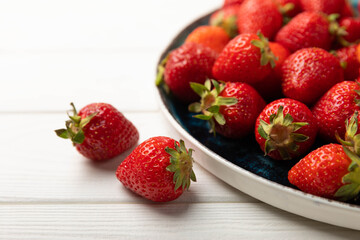 Fresh ripe strawberries in a plate on a white wooden background.Vegetarian organic berry.Healthy food.Vitamins.Copy space.Space for text