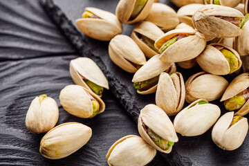 fresh salted pistachios on a black stone wooden rustic background