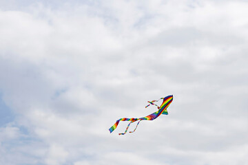 Colorful blue sky with white fluffy clouds and a flying colored kite