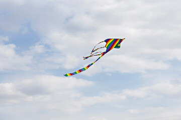 Colorful blue sky with white fluffy clouds and a flying colored kite
