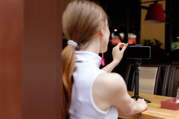 woman looks moc-ap of a smartphone and takes a selfie in a restaurant. close-up