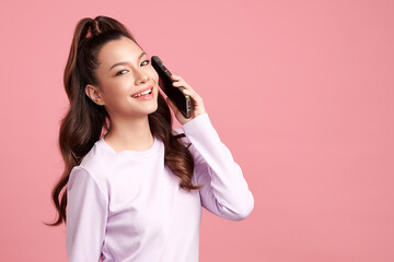 Beautiful young asian women smiling with smartphone chatting with partners online on pink background,