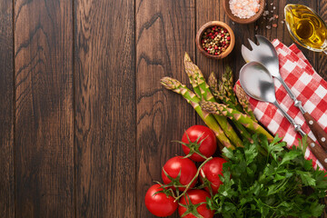 Parsley, parsley, tomato, garlic, olive oil, pepper, salt and salad fork and spoon on wooden cooking background. Food cooking background. Ingredients for cooking food background. Mock up. Top view.