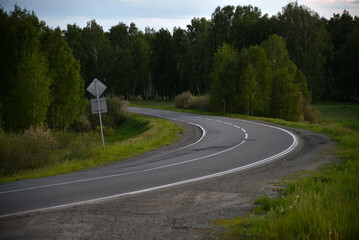 Asphalt road in the forest in the evening