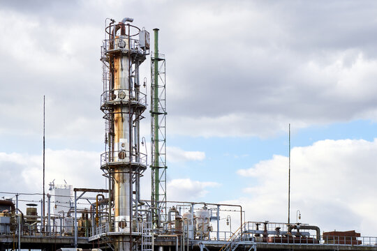 Old methanol distillation rectification refinery column towers under cloudy sky with lightning rod for lightning protection at petrochemical plant enterprise. Industrial background with copy space.