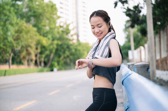 Portrait beautiful Asia woman checking smart watch after exercise jogging	