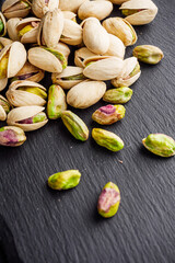 fresh salted pistachios on a black stone wooden rustic background