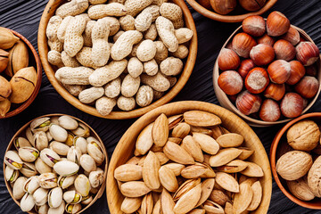 set of different nuts on a black rustic wooden background