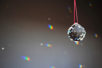 Faceted Feng Shui Crystal ball haning on a red string and casting little rainbows on the shady gray...