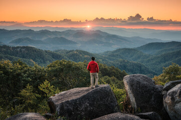 Hiker man standing on top of mountain enjoying the beautiful sunset in tropical rainforest at national park