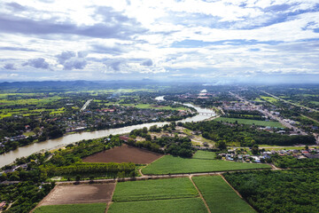 Aerial view of curved large river and village living by the water and agricultural field in countryside at suburban