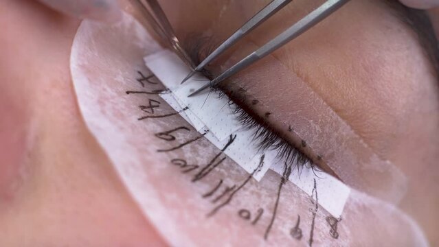 Eyelash extension procedure, close-up of a woman's eye with long eyelashes, macro, beauty saloon