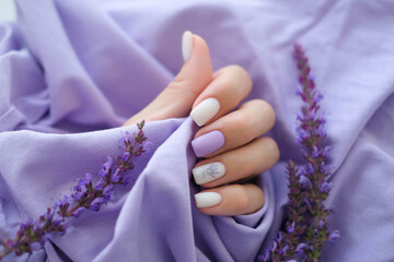 Women's hands with trendy very peri manicure and flowers in purple. Hands with spring-summer purple...