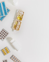 Pill box daily taking medicine, with tablets and capsules. Drugs, medication as alternative medicine for treatment and good health. Medicine dose box with pills on white table, minimal flat lay