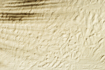 Natural fine sand stone texture with palm leaf shadow as background. Top view sand texture, sandy beach backdrop. Sunlight and shadows, summer sunny day, natural textured surface.