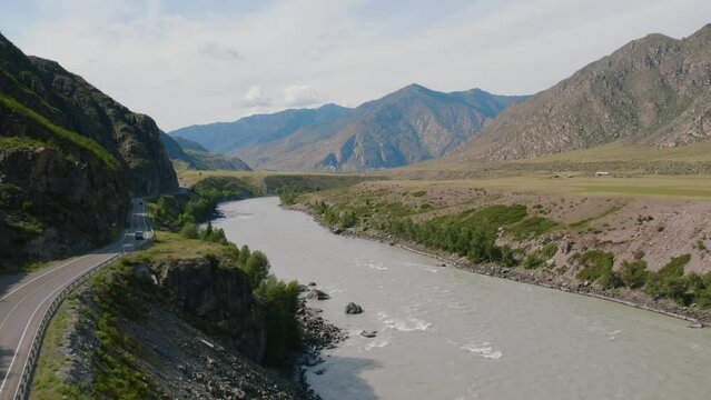 Cars on Chuya highway road between mountains and Katun river in Altai, Siberia, Russia. Beautiful summer nature landscape at during daytime. Aerial view from a drone