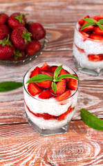 Delicious and healthy dessert with ripe strawberry, yogurt and chia seeds in a glass on a wooden table. Healthy breakfast. Сlose-up. Selective focus.