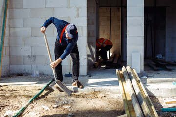 Worker builders, men in uniform and caps, labors, wetbacks preparing basement floor for building,...