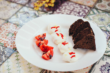 cherry tomatoes with mozzarells and black bread, drizzled with balsamic sauce.