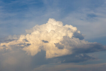 Huge white cumulus cloud against blue sky background