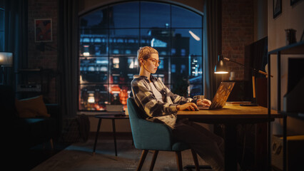 Young Attractive Woman Using Laptop Computer in Stylish Loft Apartment in the Evening. Creative...