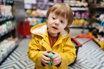 child in the market with a grocery cart buys a ball