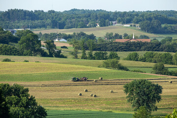 Amish farmer in the distance making hay bales in his field | Holmes County, Ohio