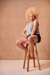 Studio Portrait Shot Of Body Positive Albino Woman Sitting On Stool