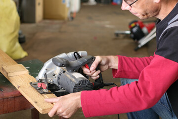 a person saws a pine plank in the garage