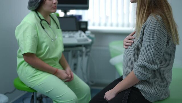 Blurred doctor talking with unrecognizable pregnant patient sitting in hospital. Caucasian gynecologist consulting Caucasian woman telling bad news. Medicine problems and health care