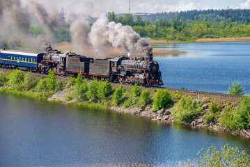 Steam locomotive with a retro tourist train on the dam of Lake Karmalanyarvi. Republic of Karelia