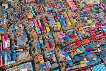 Aerial view of traditional village fair in Bangladesh. Colorful tents of temporary shops make it look like blocks of tetris game.  Portable ferris wheel
