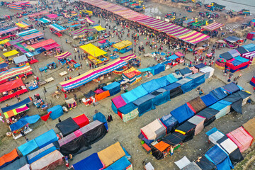 Aerial view of traditional village fair in Bangladesh. Colorful tents of temporary shops make it look like blocks of tetris game.  Portable ferris wheel