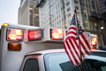 Close-up of American flag against red flasher light of siren of ambulance car. Themes emergency, rescue and help. .