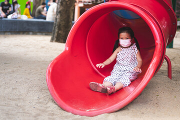Portrait image child 5-6 years old. Asian girl playing slider at playground. Kid have fun with...