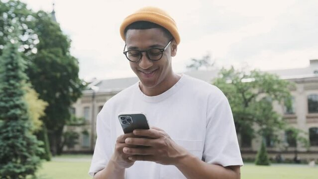 Portrait of an attractive young African American male student texting holding his phone.