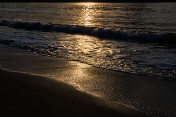 伊豆の弓ヶ浜の砂浜と波に反射する朝日の光