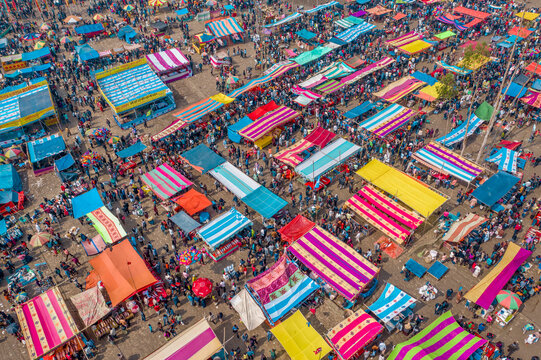 Aerial view of traditional village fair in Bangladesh. Colorful tents of temporary shops make it look like blocks of tetris game.  Portable ferris wheel