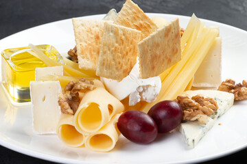 Assorted cheeses in a plate. On a gray background.