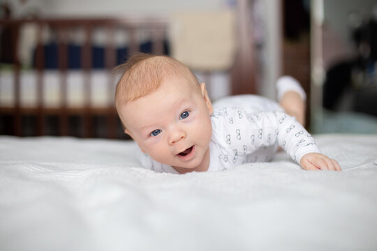 Blue-eyed 3-month-old baby learning to roll over