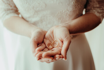 Detail of a woman's hands holding two wedding rings, vintage style.