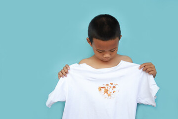 Asian kid looking dirty sauce or food stain on shirt from eating in meal. dirty stain for cleaning concept.