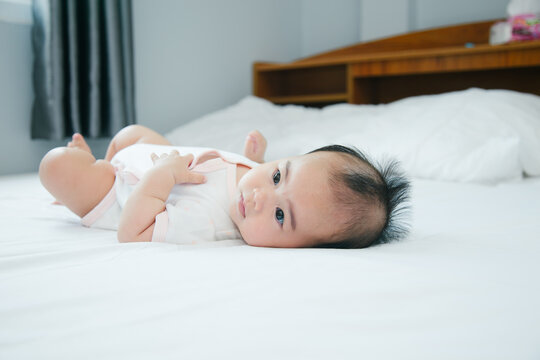 Cute little asian baby lying on bed with soft blanket indoors