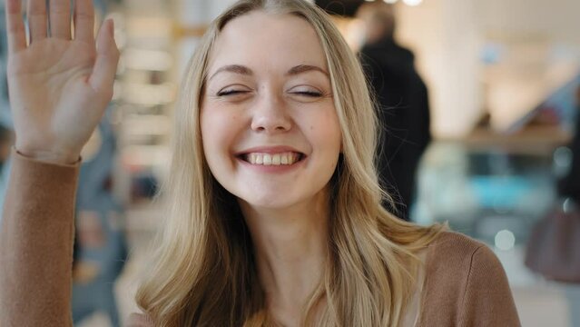 Portrait indoors Caucasian blonde girl friendly woman smiling peeping somebody waiting looking away lady waving hello greeting invitation come up welcome symbol meeting date coming here gesture invite