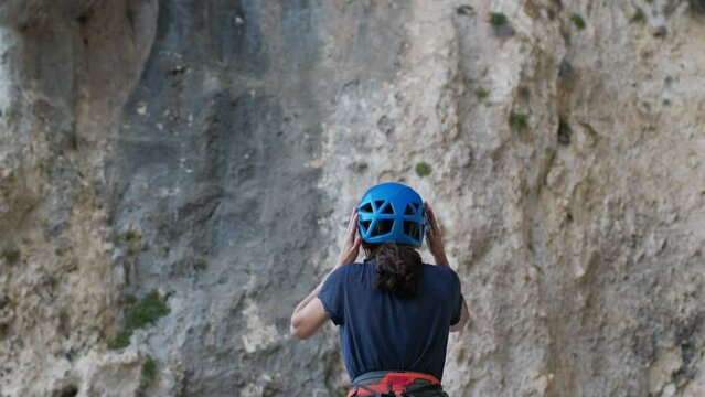 Woman putting on safety helmet, climbing safety, rock climbing and mountaineering equipment