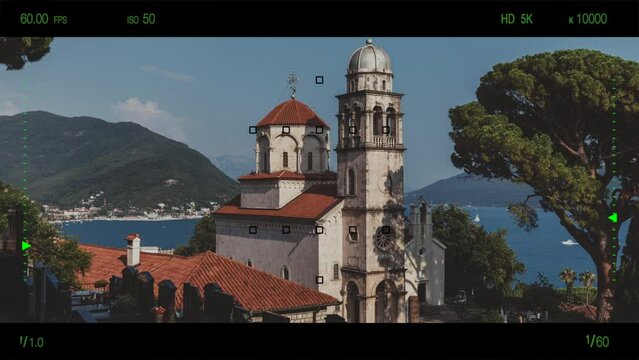 A look through photo camera at Savina Monastery, Serbian Orthodox monastery of three churches near the city Herceg Novi in the Bay of Kotor. Summer landscape with mountain and sky in sunset time