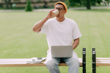 African American student sipping coffee sitting outdoor in the campus.